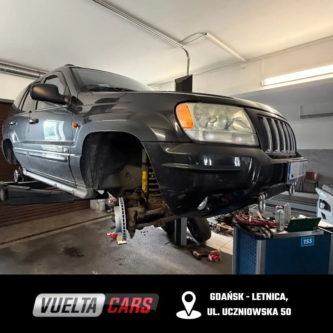 Ciemny Jeep na podnośniku ze zdjętym przednim kołem w Vuelta Cars